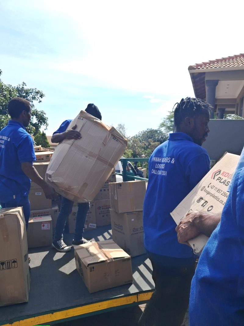 Three Panah crew in branded blue shirts passing sealed cartons up onto the back of a bakkie.