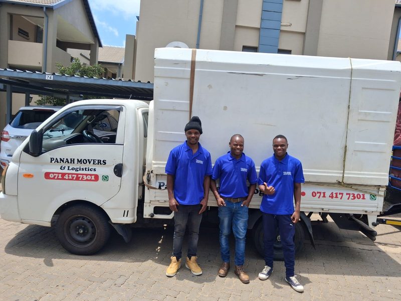 Three Panah crew in branded blue shirts standing in front of the company bakkie at a complex.